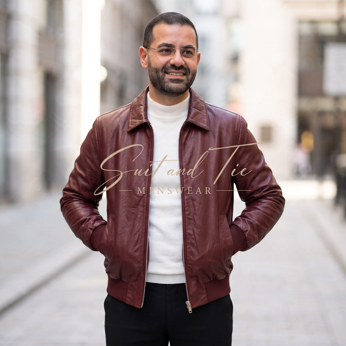 A man wearing a burgundy leather jacket over a white turtleneck and black trousers, standing in a blurred city street. A large 'Suit and Tie MINSWEAR' watermark is overlaid across the center.