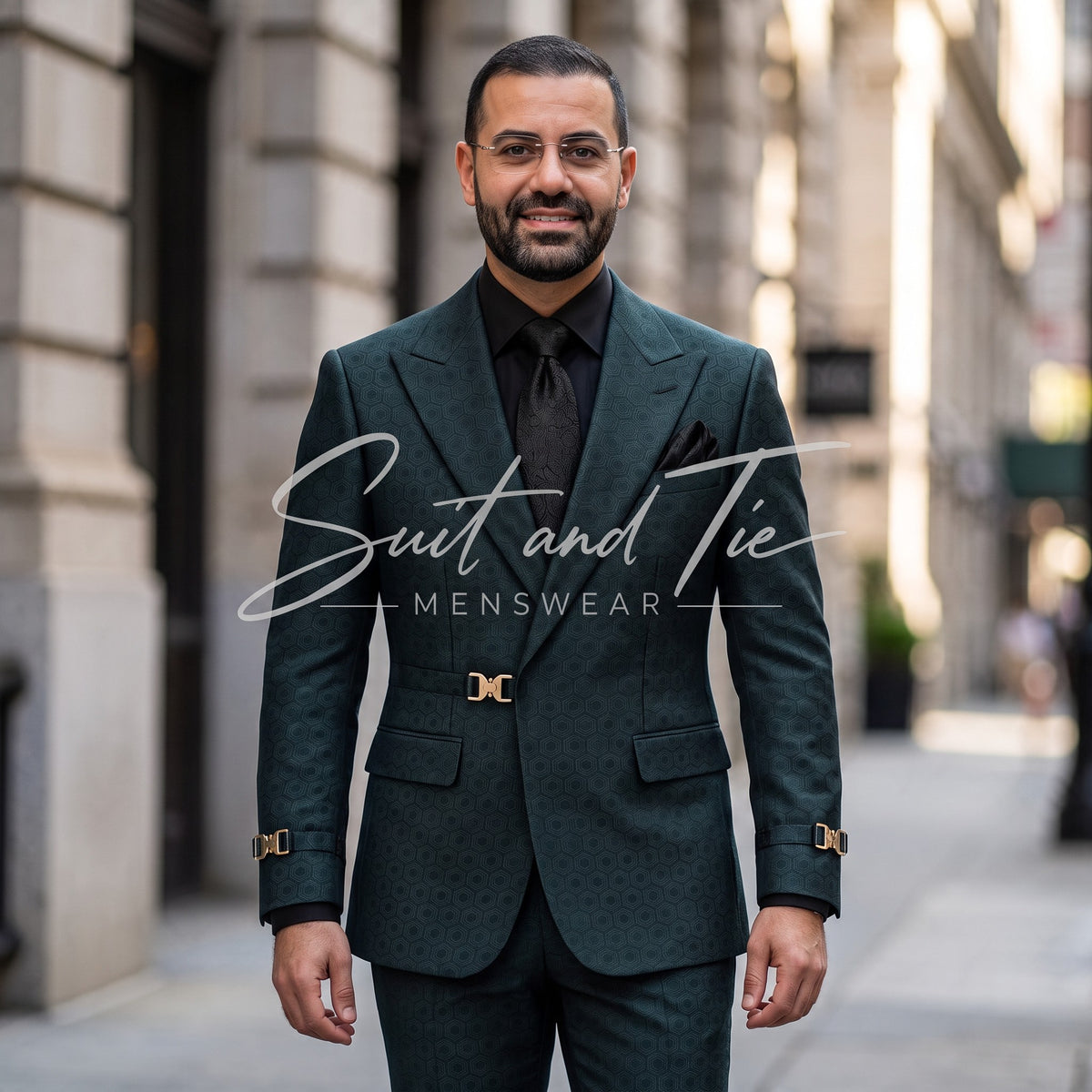 A man wearing a dark green patterned suit with gold cufflinks, a black shirt, and a black tie, standing on a city street. A white watermark reads 'Suit and Tie Menswear'.