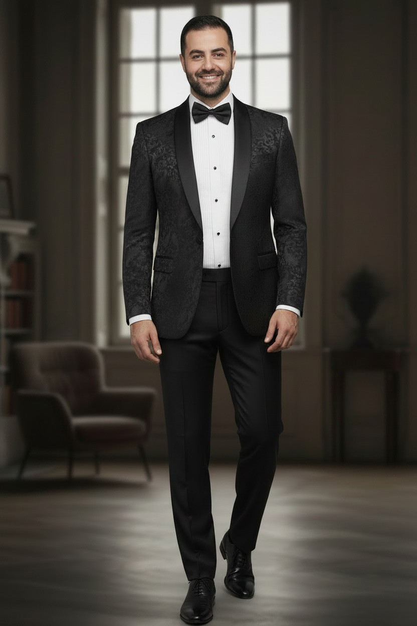 Man wearing a black tuxedo in an elegant room with large windows.