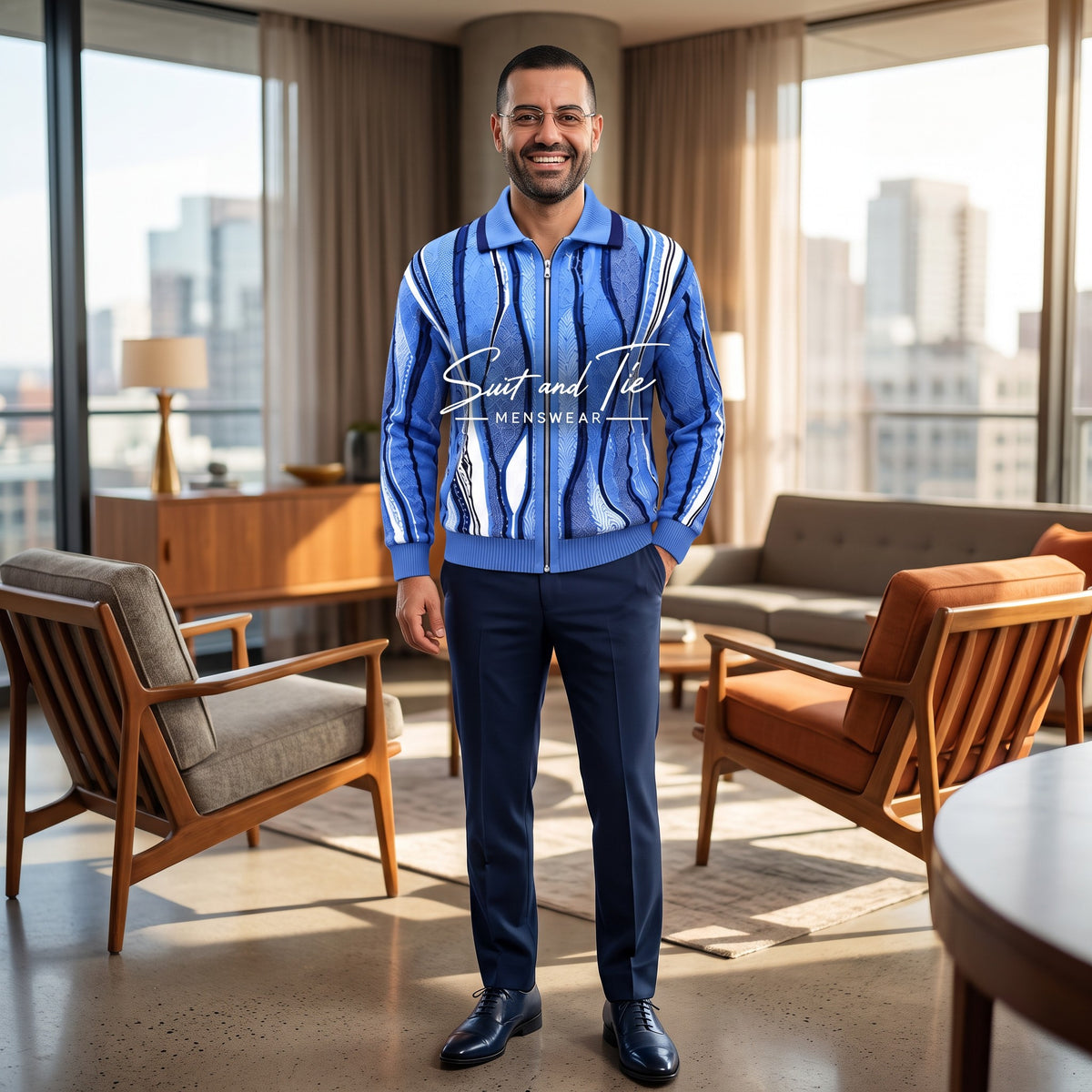 A man stands in a modern living room wearing a blue and white vertically striped zip-up jacket with 'Suits and Te' printed across the chest, paired with navy trousers and dark blue dress shoes.