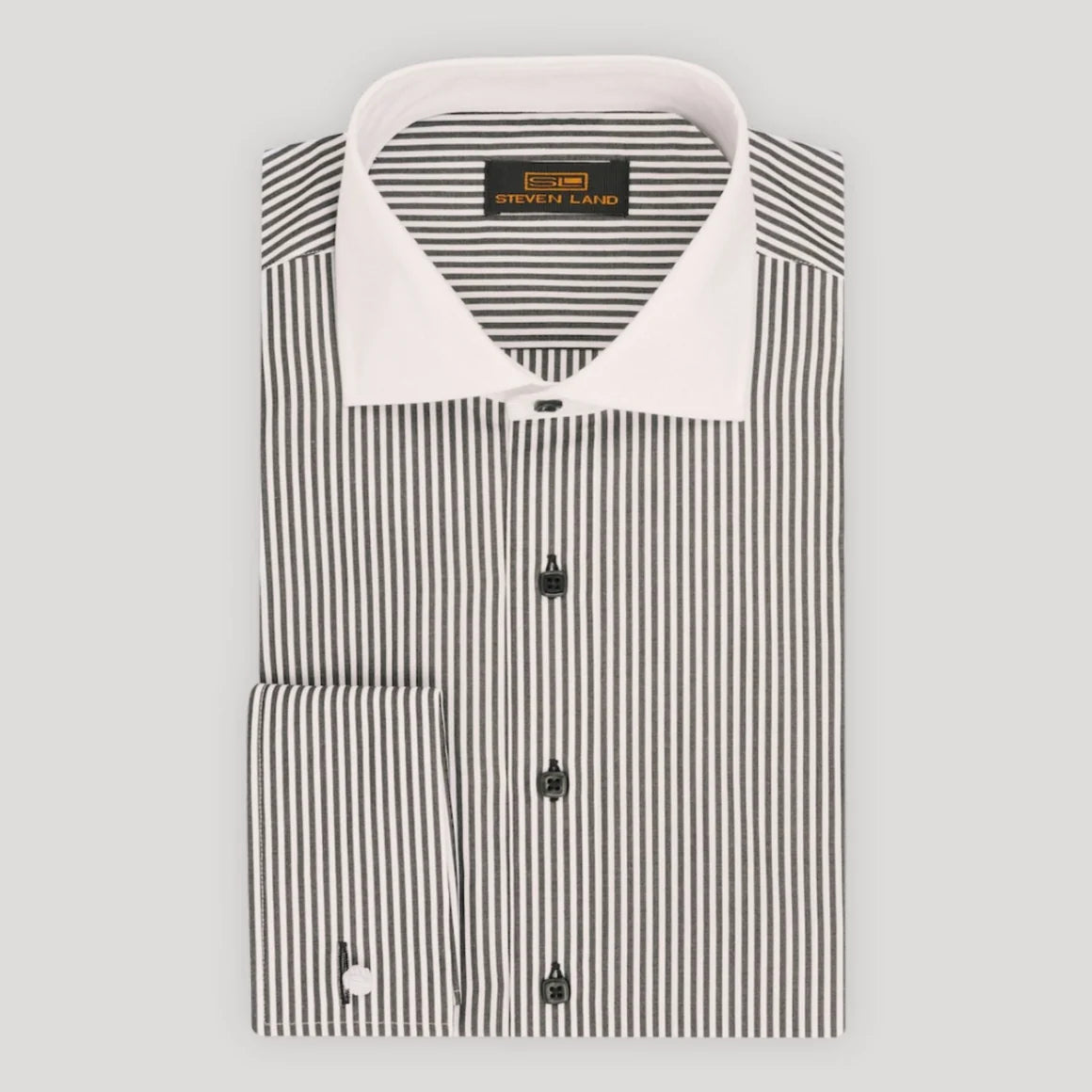 A folded long-sleeve dress shirt by Steve & Land, featuring vertical black and white stripes with a solid white collar and white buttons, displayed on a neutral light gray background.